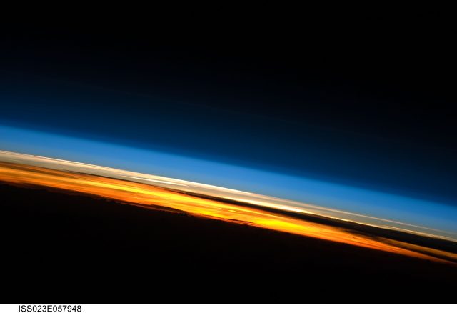 Figure 1. Earth's atmosphere as seen from the International Space Station during one of its 16 daily sunsets. This picture show the layered nature of our atmosphere: from bottom to top, black is the Earth itself, the troposphere is seen here yellowish and orange due to sunlight scattering, then the stratosphere looks white, the outer atmosphere comprising all external layers is pale blue and, finally, the outer space seems dark blue. | Credit: ISS expedition 23 crew, NASA.
