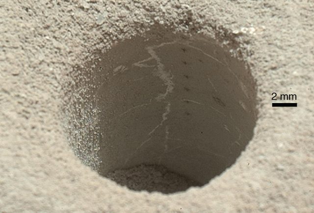 Figure 3. John Klein drilling hole at Yellowknife Bay, Gale Crater, Mars. This site provided some of the information described in the text. It reveals a mudstone of diagenetic origin. Up to eight ChemCam shoting points can be seen across the hole, used for understanding the volatile and organic composition of the sample. | Credit: NASA/JPL, Caltech/MSSS.