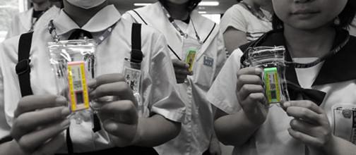 Figure. 1. Children in Fukushima with their radiation dosimeters called “glass budges.” The regional government requires children and pregnant women to wear them as a way “to calm the anxiety of the children and their guardians.” (Source http://www.jfissures.org/2012/03/21/the-occupation-and-glass-badges/)